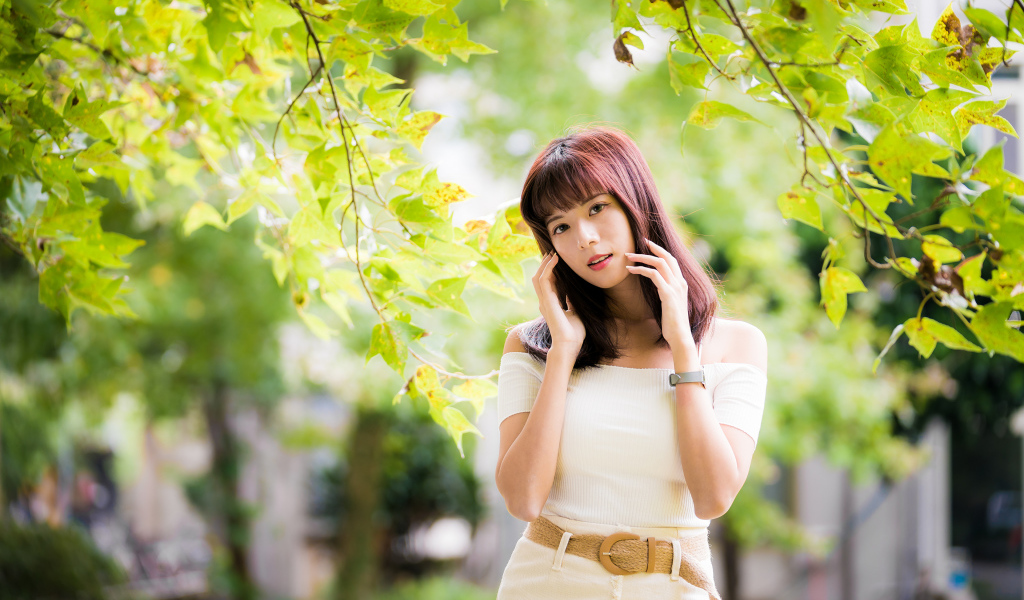Красивая азиатка в белом платье у дерева 