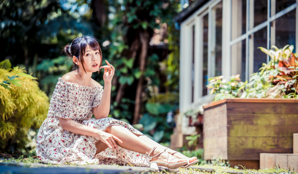 Красивая девушка азиатка в платье сидит на земле