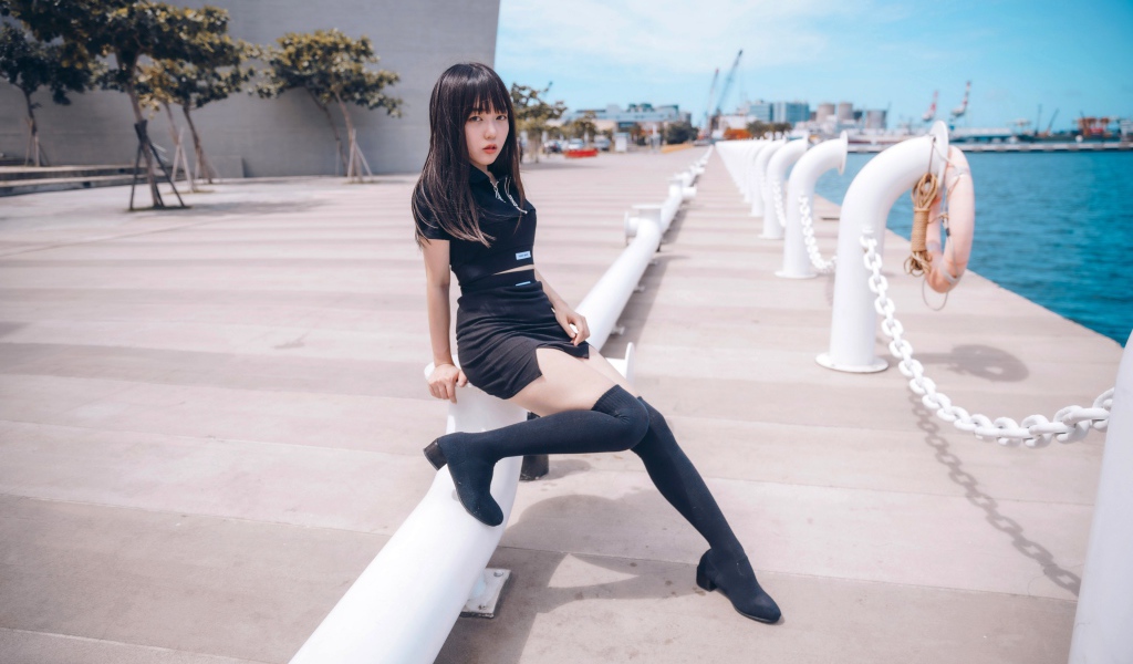 Красивая девушка азиатка в черных сапогах на причале