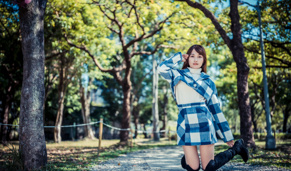 Красивая девушка азиатка стоит на коленях в парке