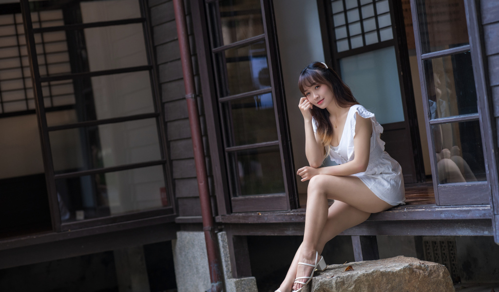 Красивая девушка азиатка сидит у двери