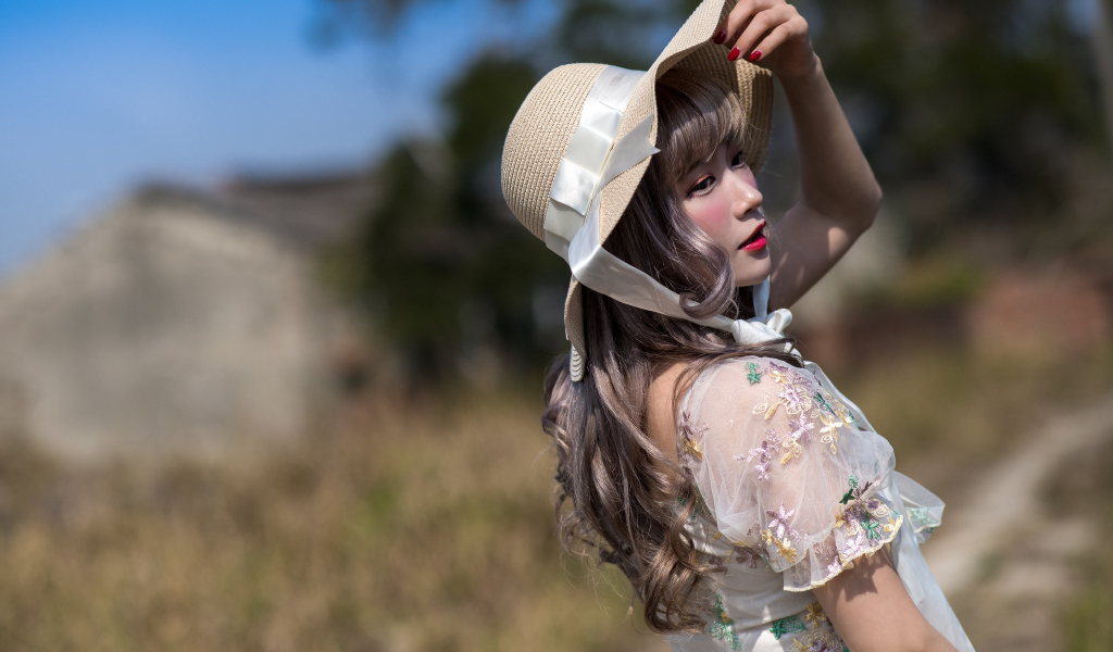 Красивая азиатка в шляпе в лучах солнца