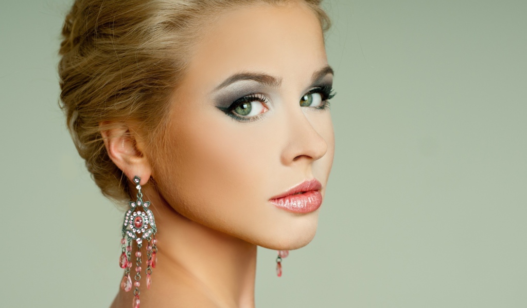 Красивая девушка блондинка с красивыми сережками на сером фоне