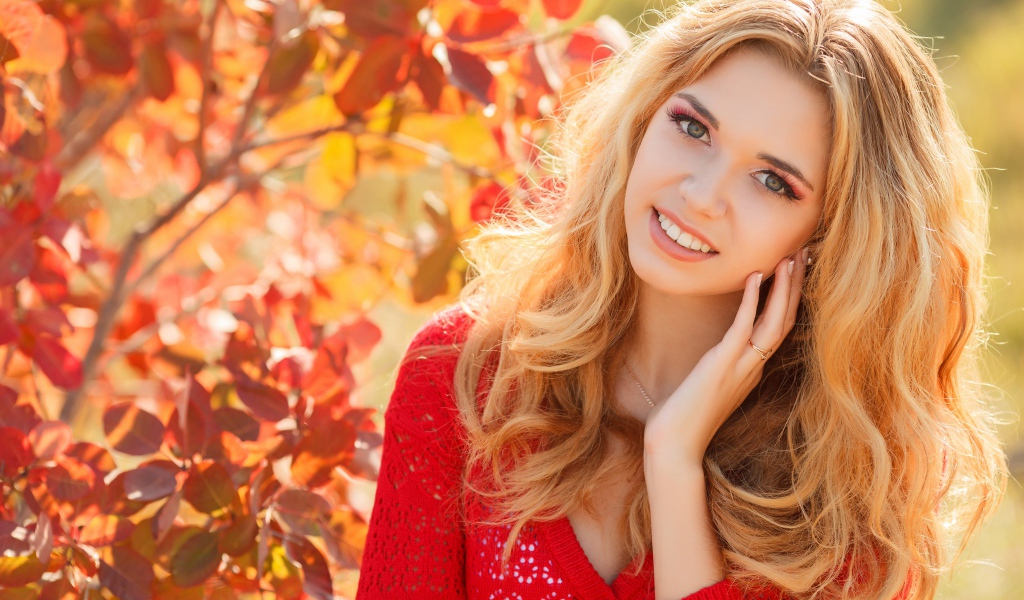 Beautiful blonde in a red sweater outdoors in autumn