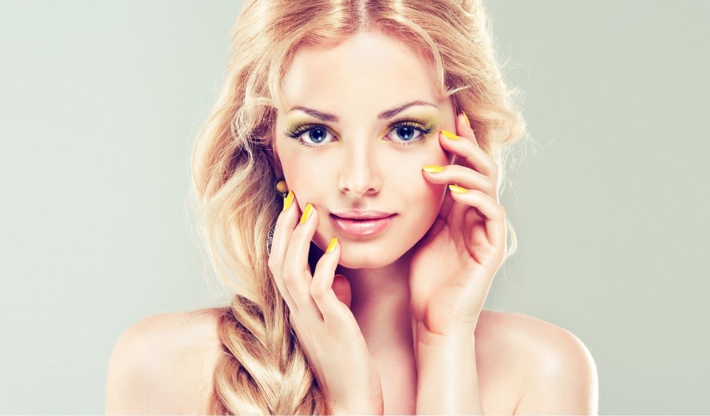 Красивая голубоглазая блондинка с желтым маникюром на руках 