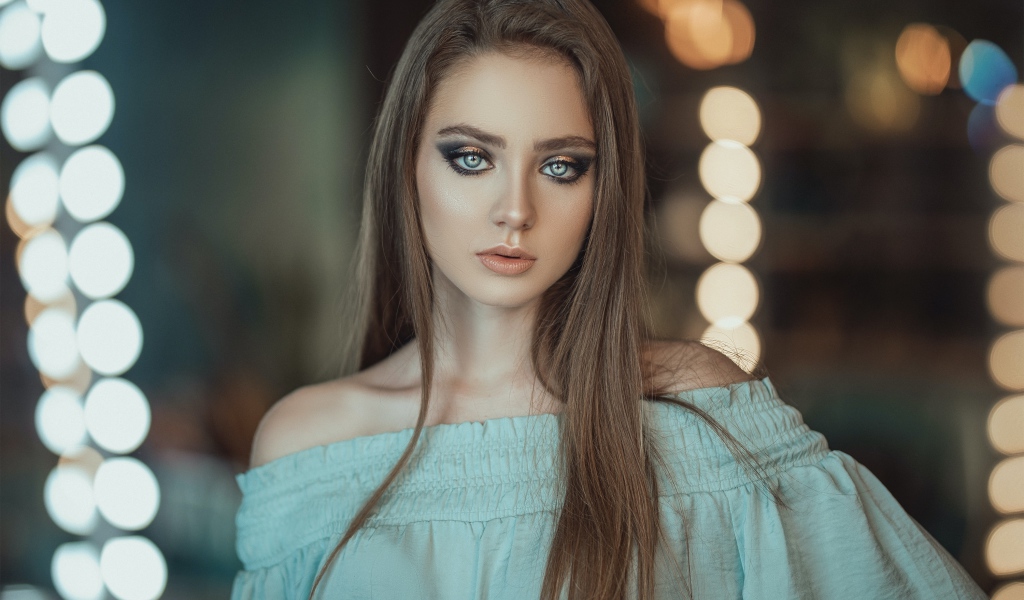 Красивая голубоглазая девушка в платье у зеркала 