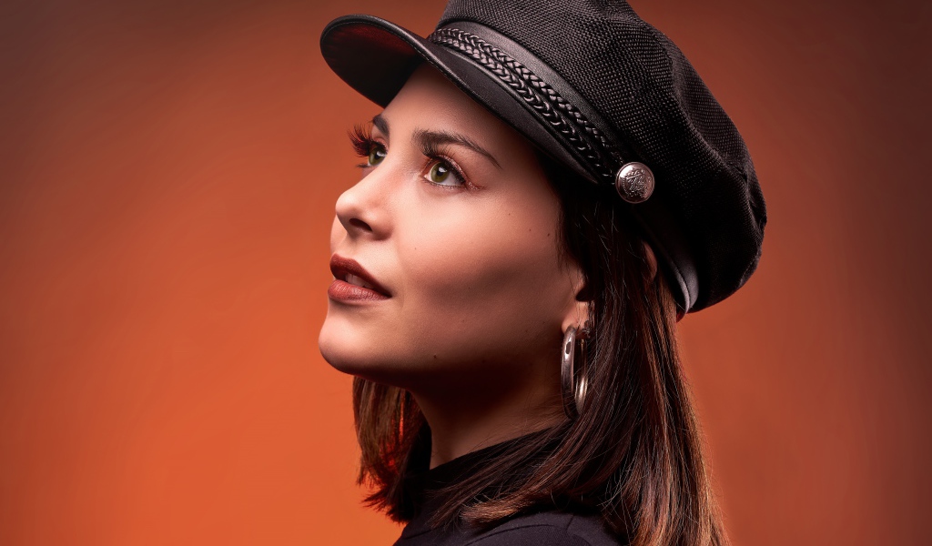 Красивая девушка в кепке на коричневом фоне