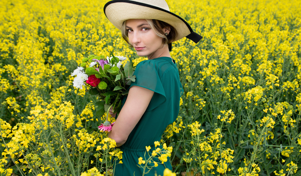 Красивая девушка в шляпе на поле с желтыми цветами летом