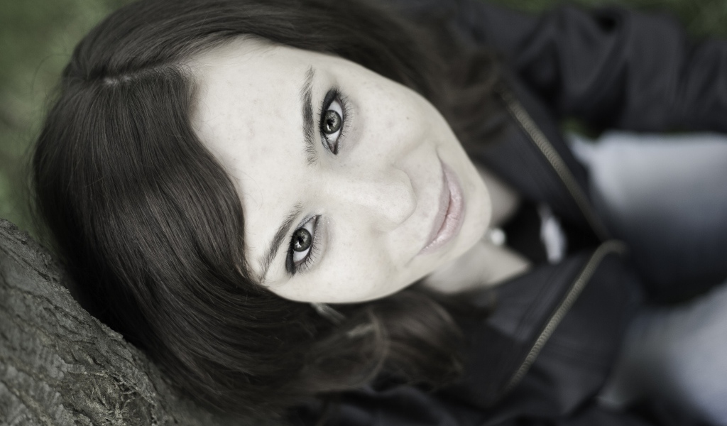 Красивая девушка смотрит вверх сидя под деревом  