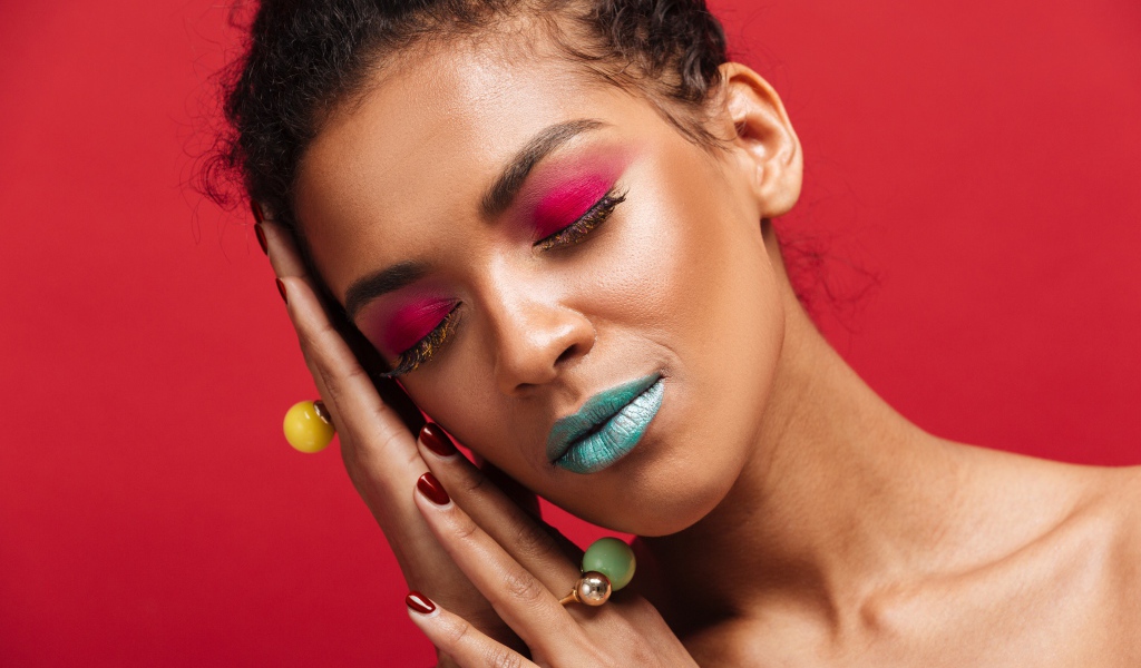 Красивая девушка с ярким макияжем на красном фоне