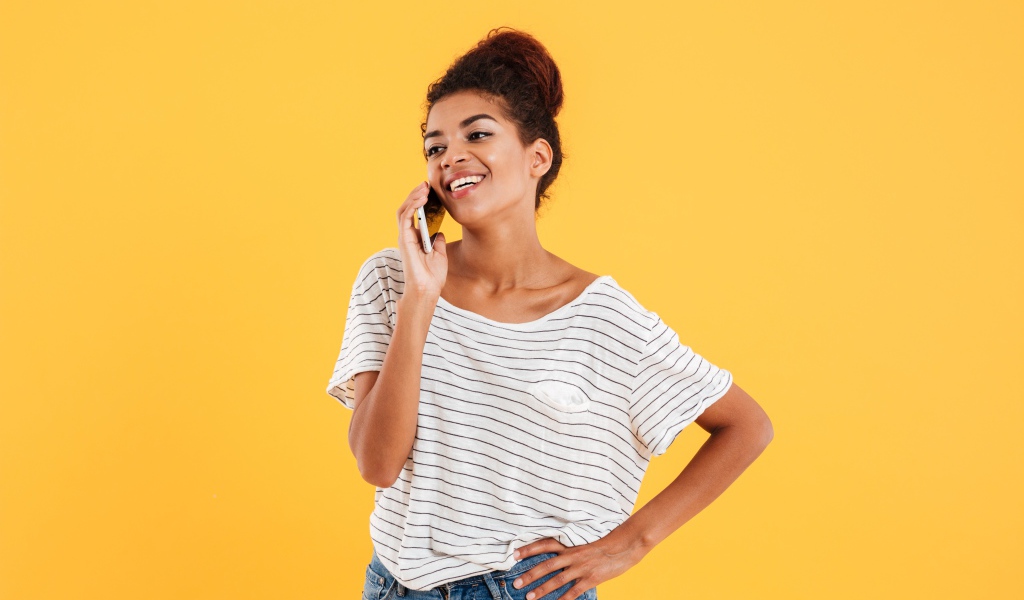 Красивая девушка со смартфоном на желтом фоне