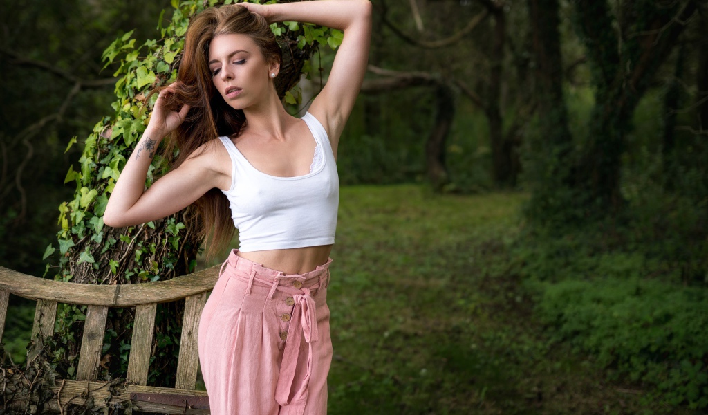 Красивая стройная девушка стоит у дерева 