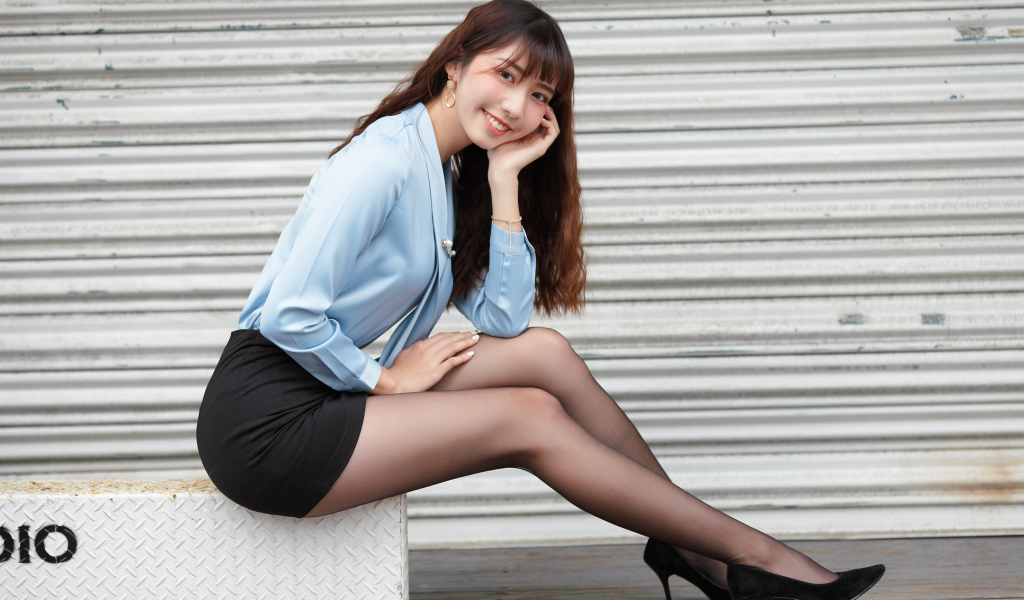 Красивая улыбающаяся девушка азиатка в черной юбке 