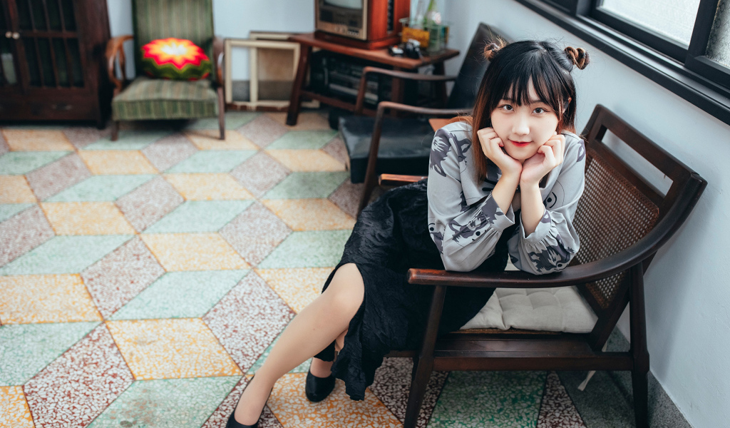 Красивая молодая азиатка сидит в кресле