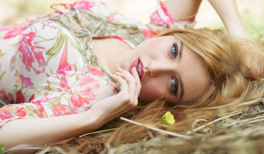 Красивая молодая блондинка лежит на траве