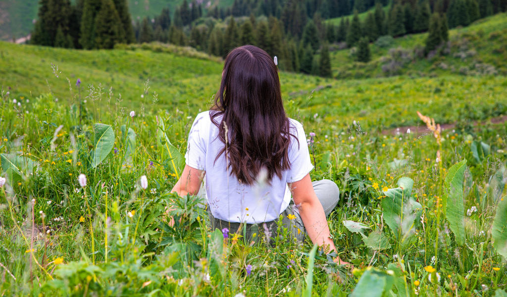 Красивая молодая девушка сидит на поле с зеленой травой