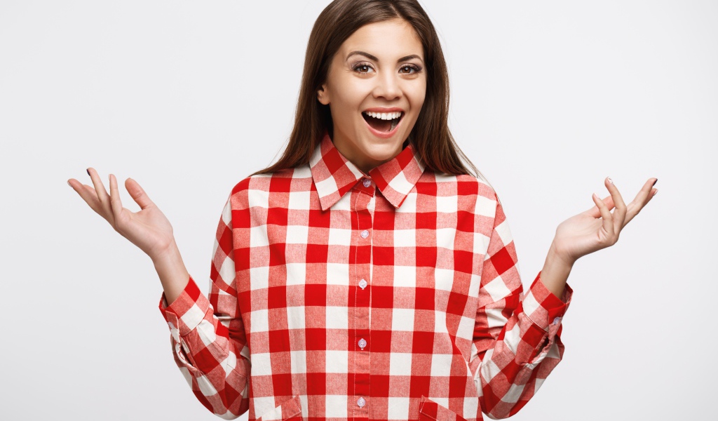 Веселая девушка в клетчатой рубашке на белом фоне 