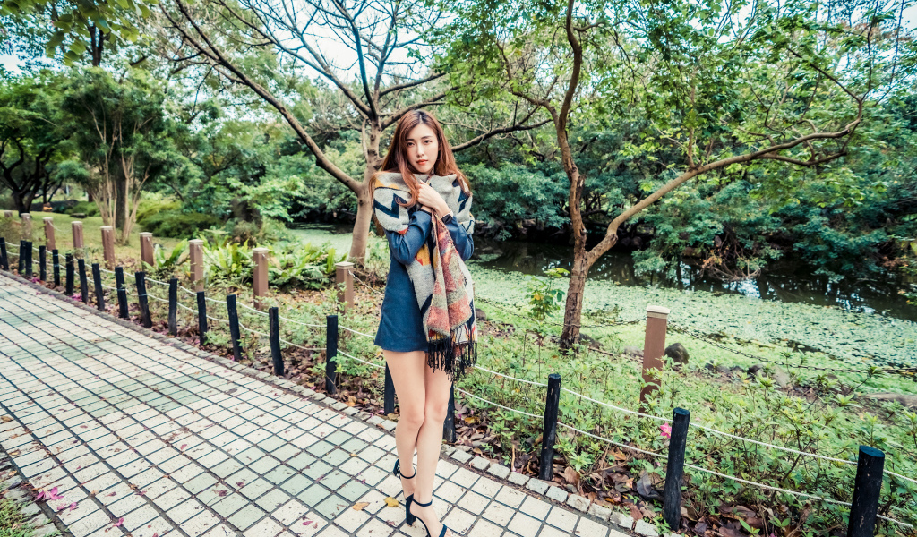 Милая девушка азиатка стоит в осеннем парке 