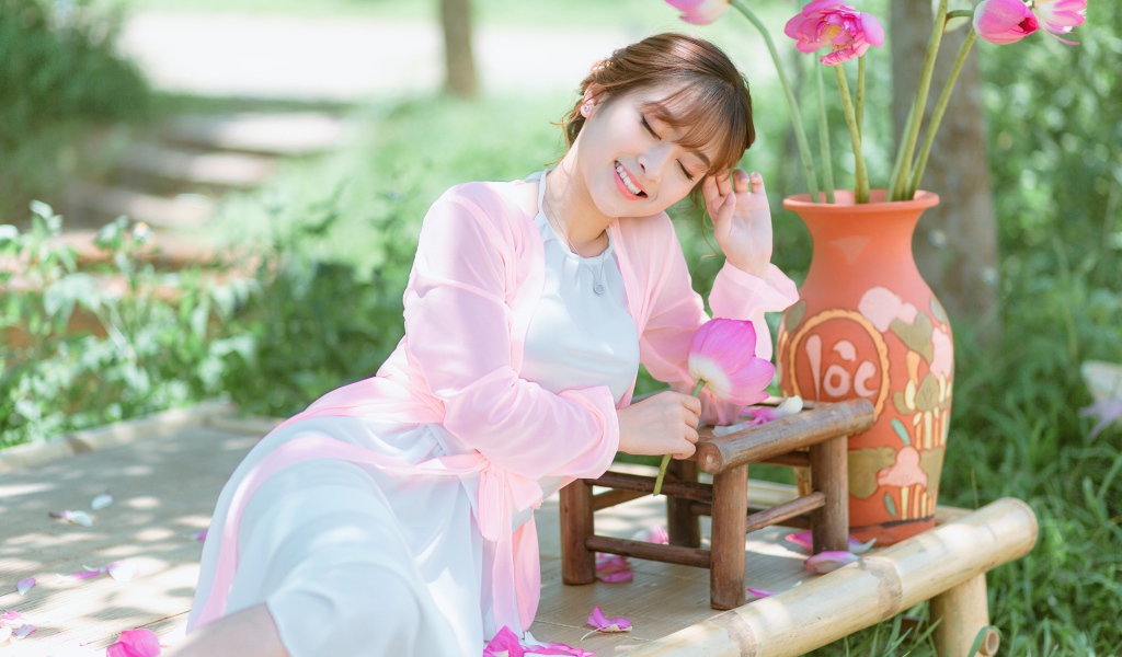 Мечтательная девушка азиатка с цветами лотоса