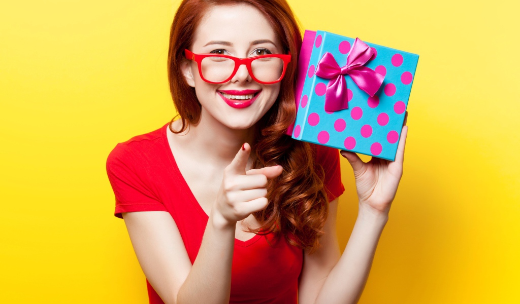 Девушка в очках с подарком в руке на желтом фоне