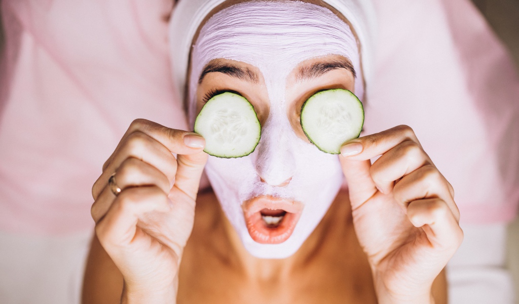 Девушка с маской на лице с огурцами на глазах 