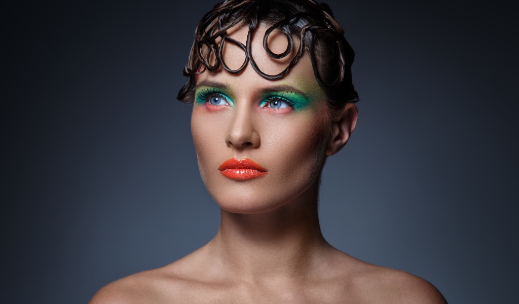 Девушка с ярким макияжем на сером фоне 