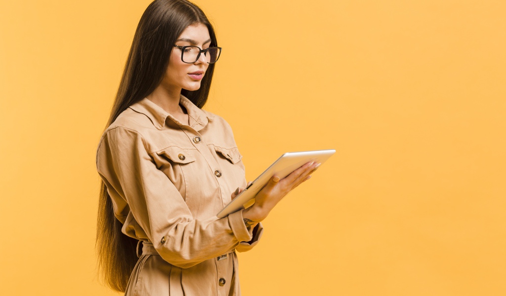 Девушка с планшетов руках на желтом фоне