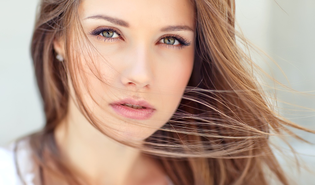 Волосы развеваются ветром на лице у девушки