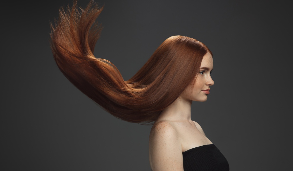 Волосы подняты вверх у красивой девушки на сером фоне