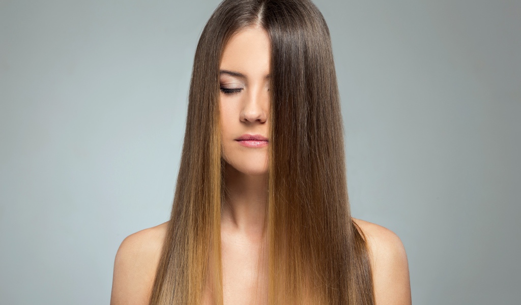 Длинноволосая шатенка с закрытыми глазами на сером фоне 