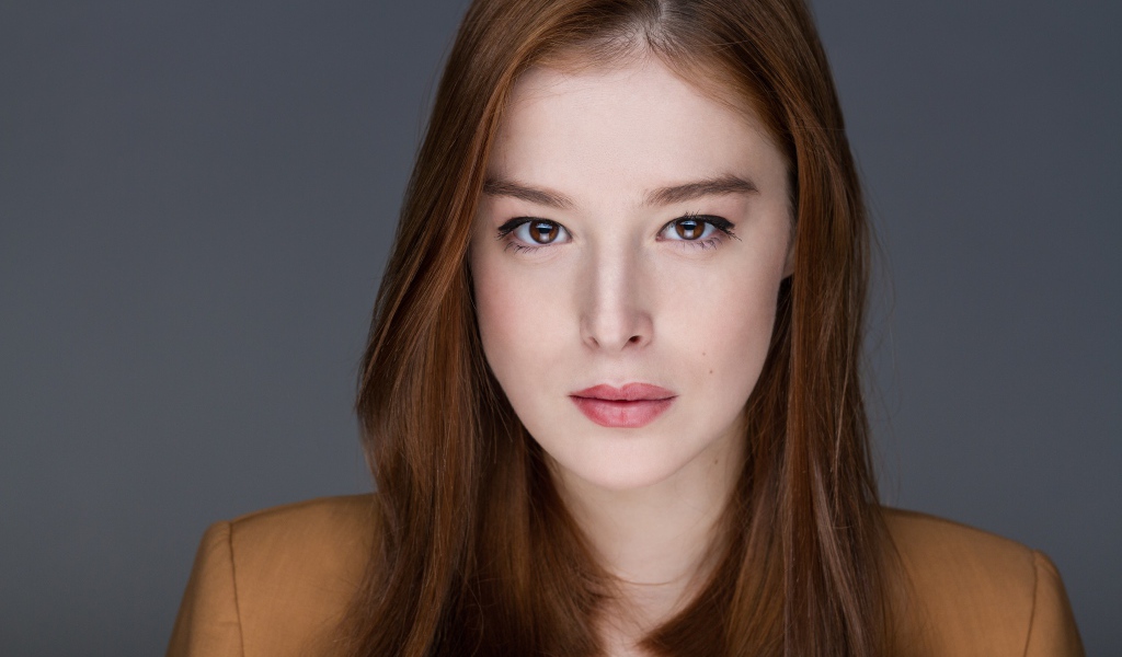 Рыжеволосая  молодая девушка на сером фоне