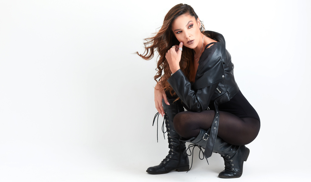 Девушка рокерша в черной куртке на белом фоне 