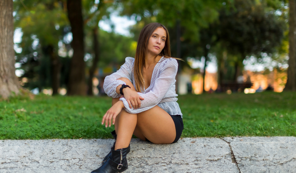 Грустная девушка сидит на земле в парке 