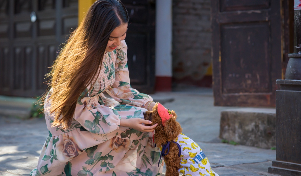 Улыбающаяся девушка азиатка с собакой 