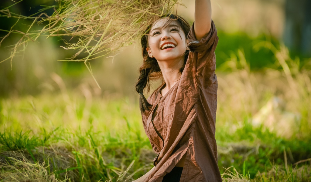 Улыбающаяся девушка азиатка с травой в руках 