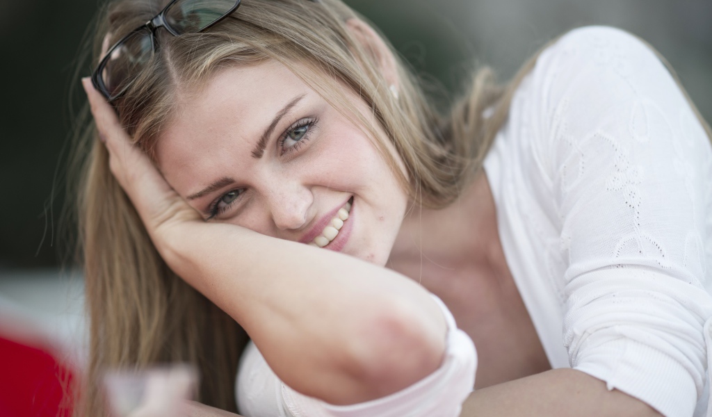 Улыбающаяся девушка блондинка с очками на голове