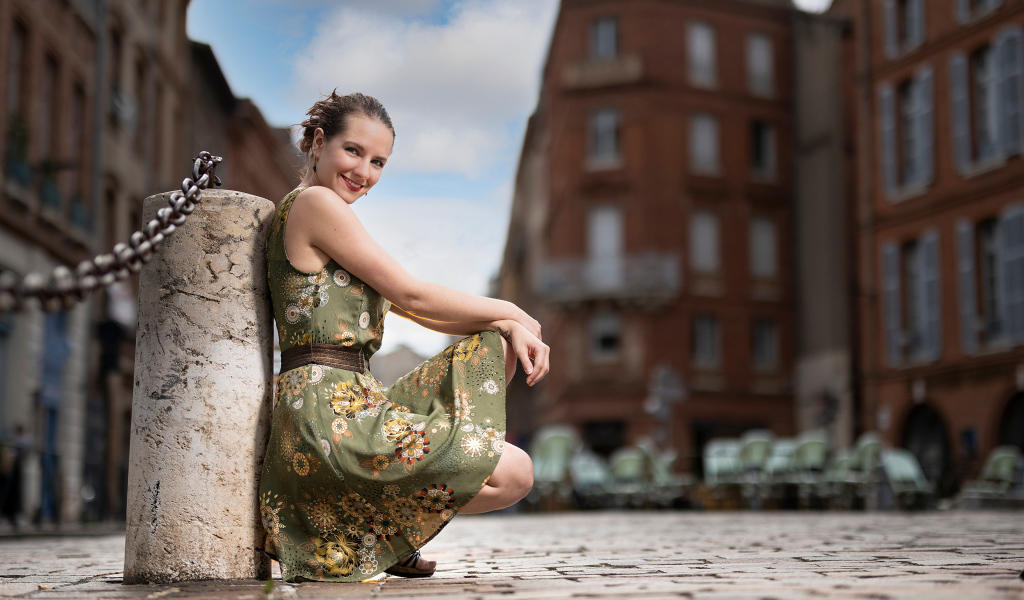 Улыбающаяся девушка в платье на улице города