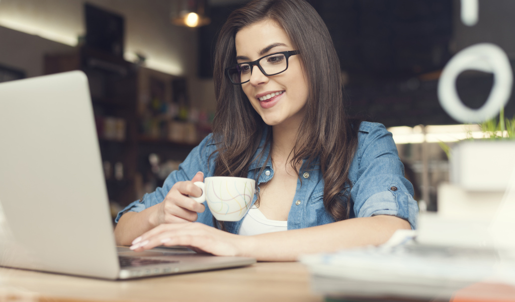 Улыбающаяся девушка в очках с ноутбуком