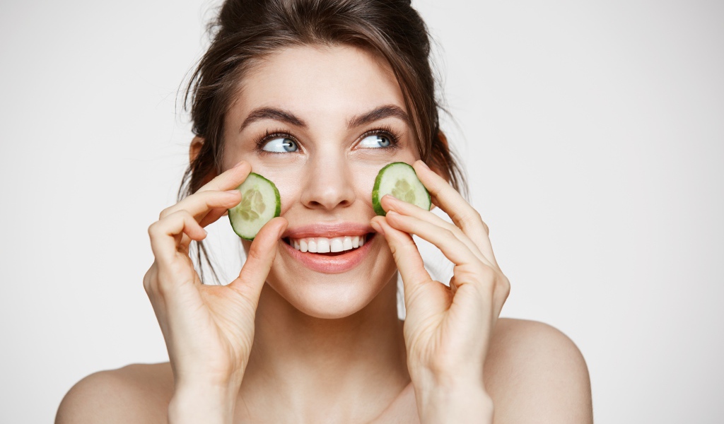 Улыбающаяся девушка с огурцами на лице