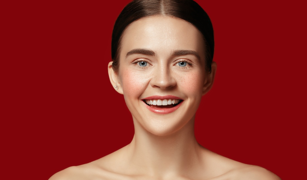 Улыбающаяся молодая девушка на красном фоне