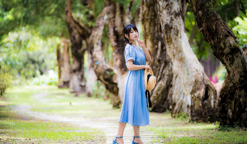 Стильная девушка азиатка в голубом платье в парке 