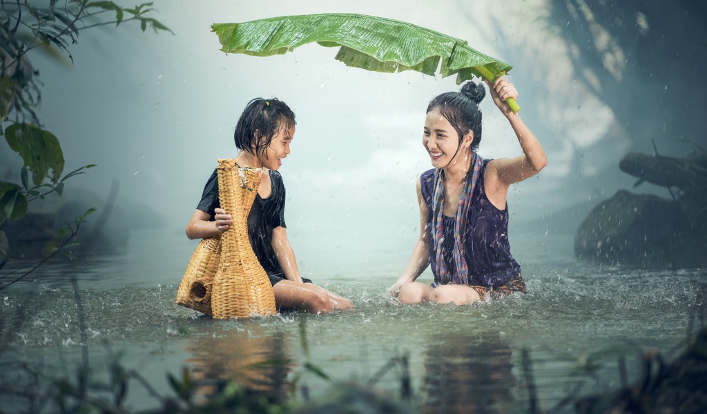 Две девушки азиатки под дождем в воде