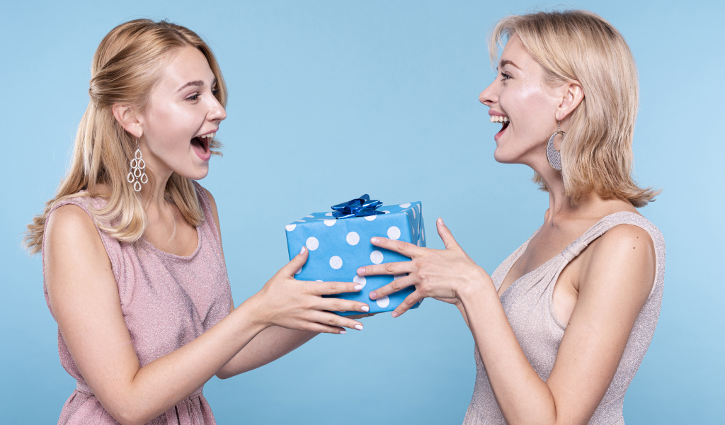 Две подруги блондинки с подарком на голубом фоне