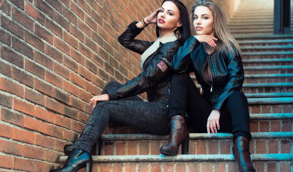 Две красивые девушки сидят на ступенях 