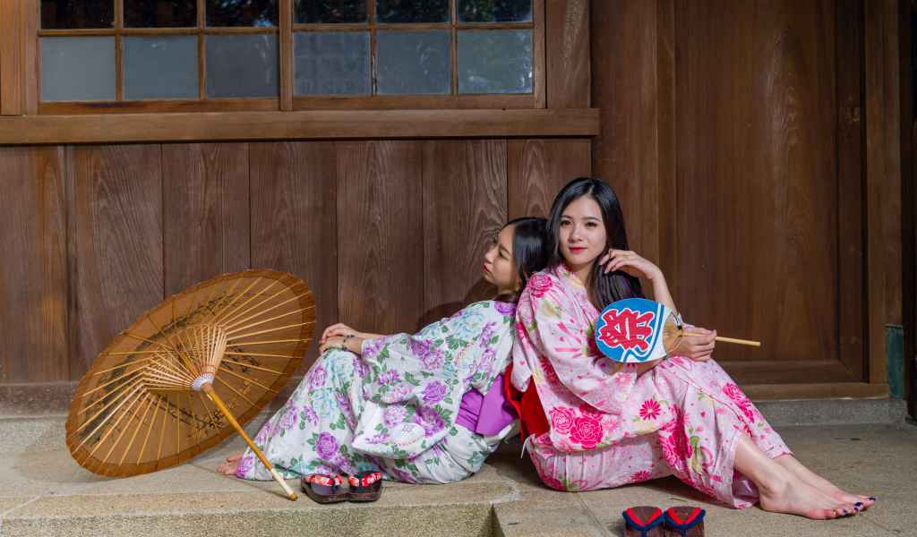 Две молодые девушки в кимоно сидят на полу