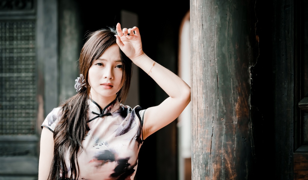 Молодая девушка азиатка стоит у столба 