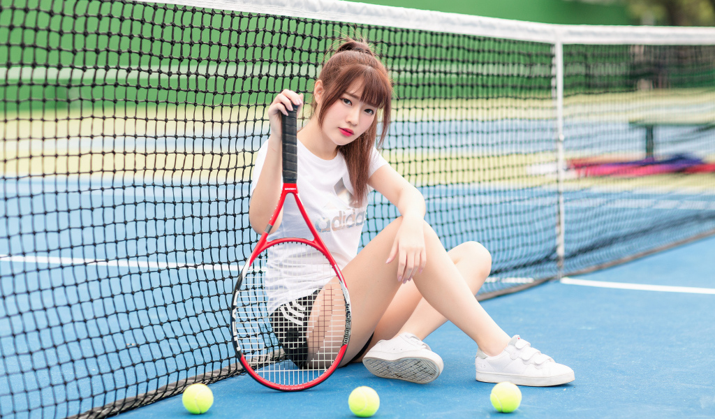 Молодая девушка азиатка с ракеткой на корте