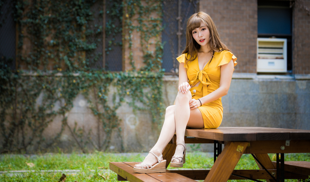 Молодая азиатка сидит в парке на столе 