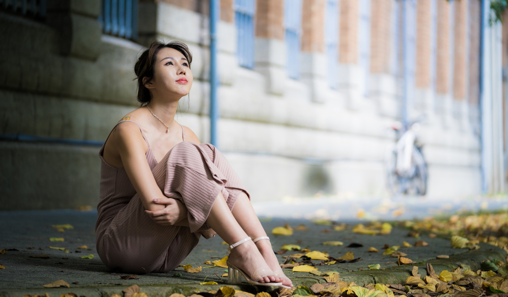 Молодая девушка азиатка сидит на земле с листьями 