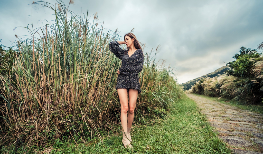 Молодая девушка азиатка стоит у зеленой травы